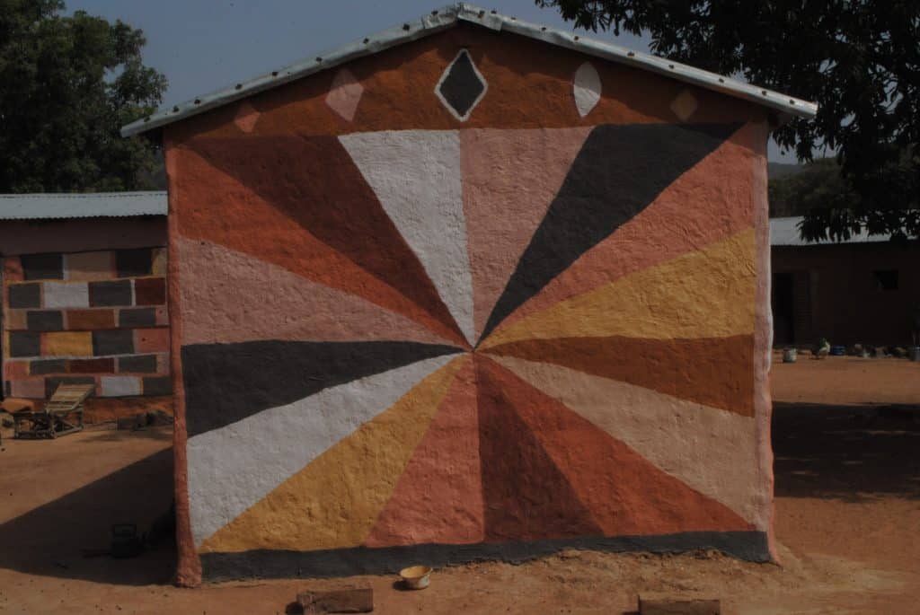 Motifs peints aux pigments naturels sur un mur en terre.
